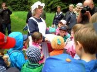 Frau Holle erklärt den Kindern, weshalb es nicht schneit, obwohl sie die Kissen schüttelt.